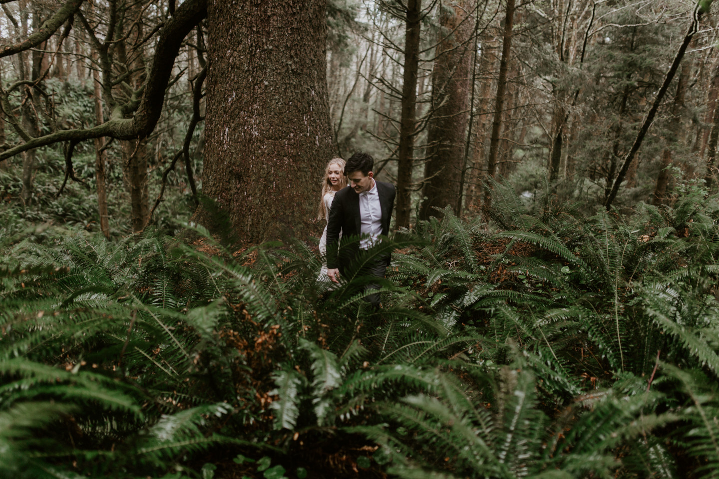Hannah and Grant walk through the ferns in Cannon Beach, Oregon during their Oregon coast elopement. Wedding photography in Portland Oregon by Sienna Plus Josh.