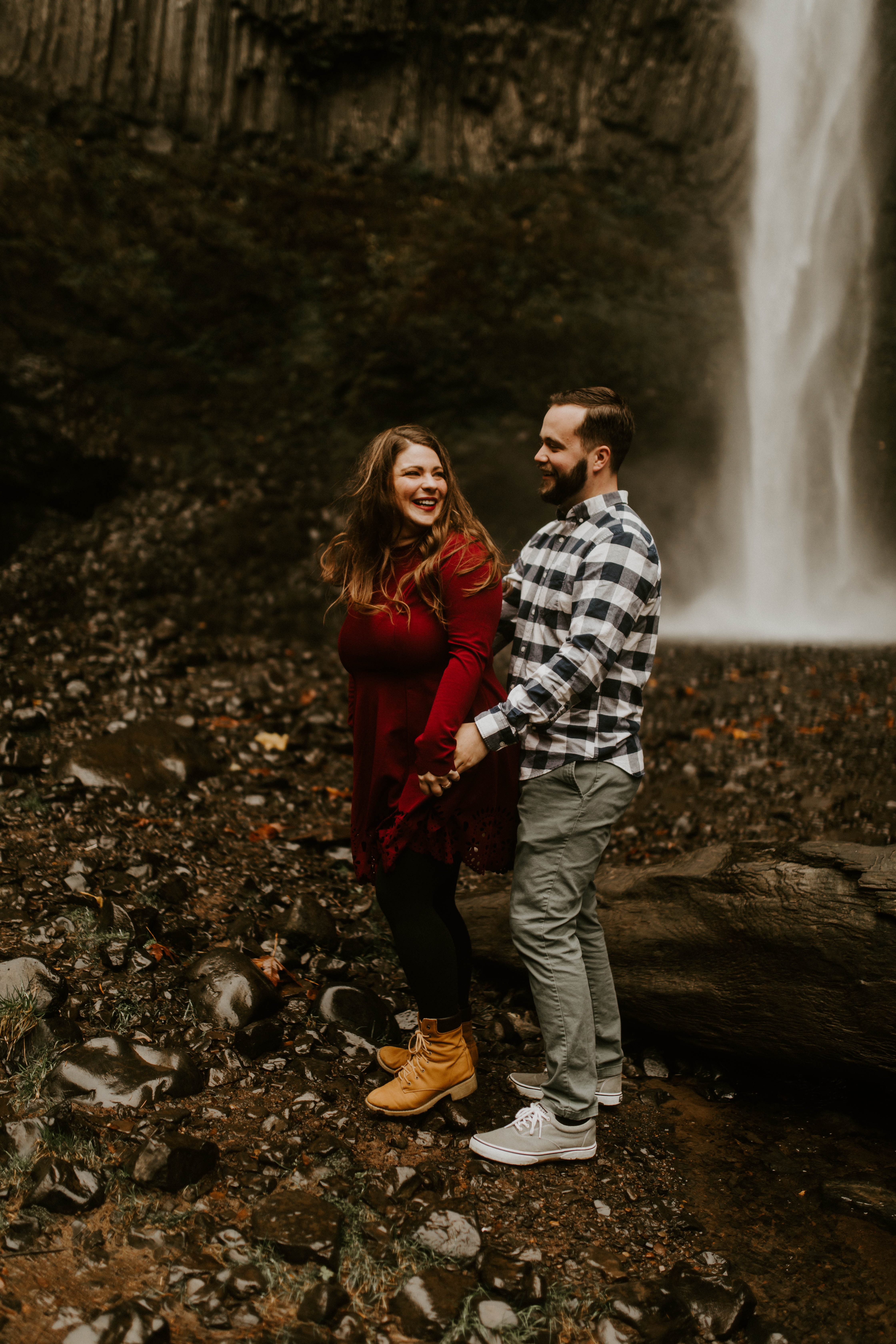 Brandon and Allison smile at each other in front of Latourell Falls. Engagement shoot by Sienna Plus Josh.