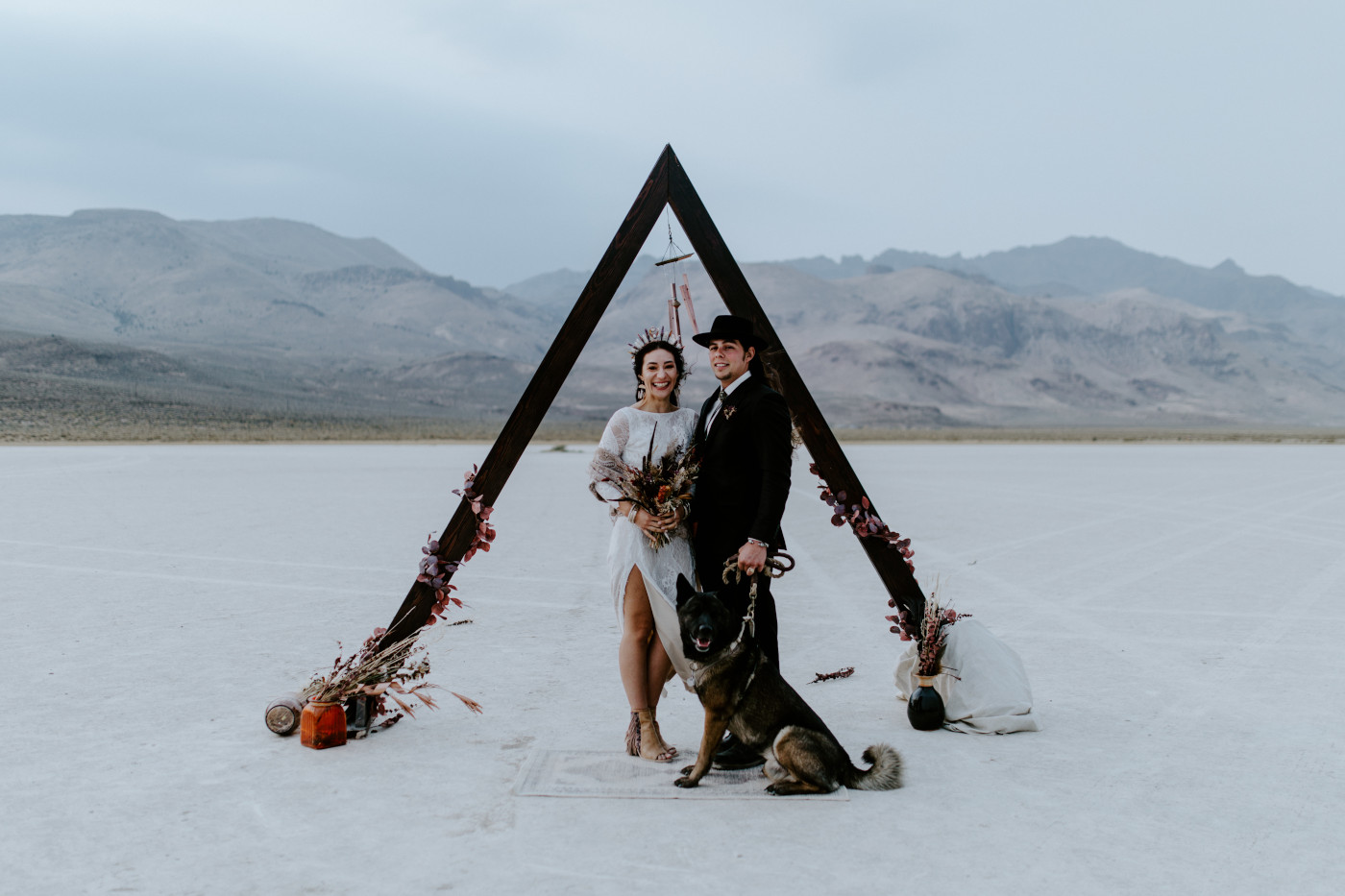 Emerald and Cameron take a picture with their dog while standing at the altar.