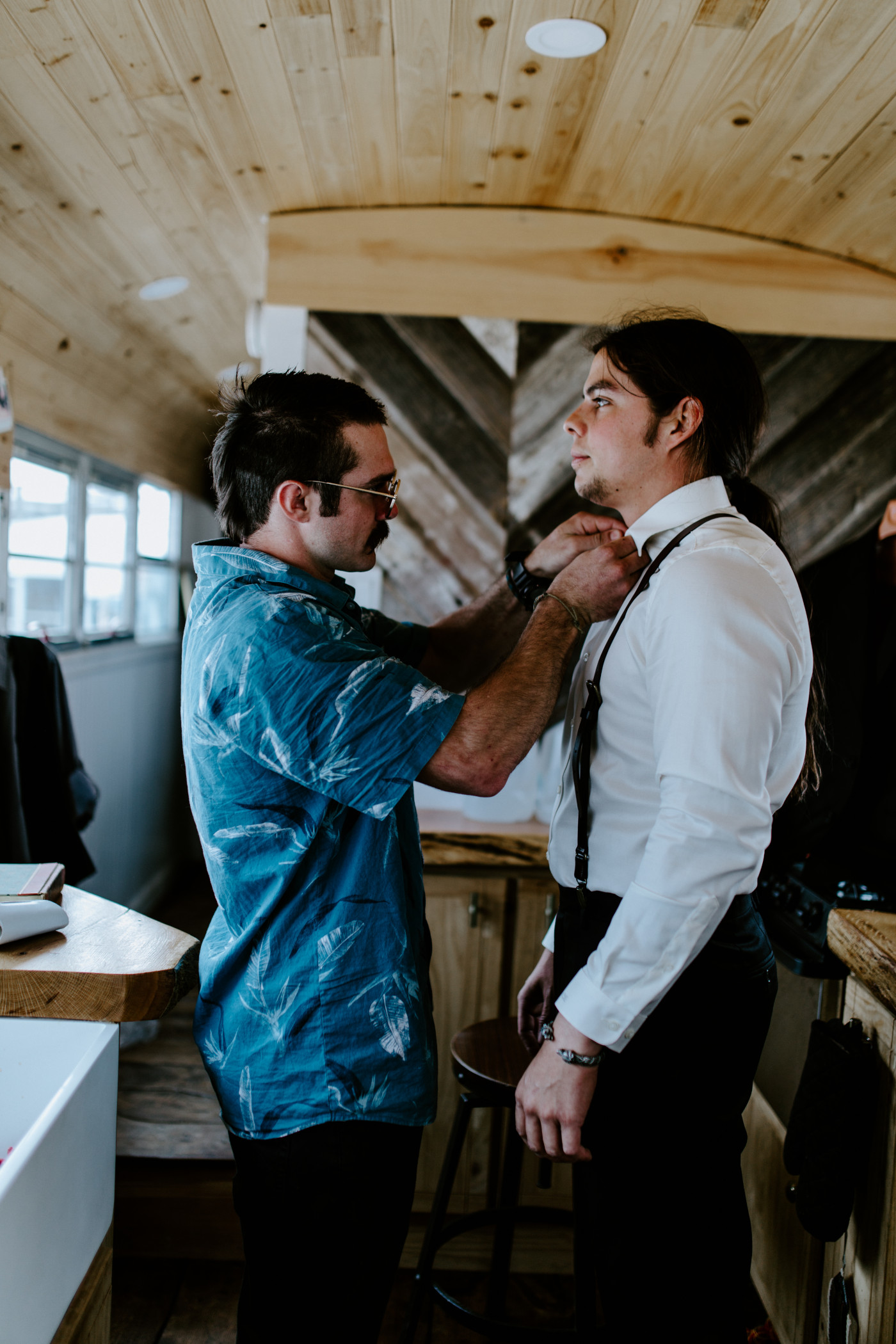 Cameron's friend helps him fit his bolo tie.