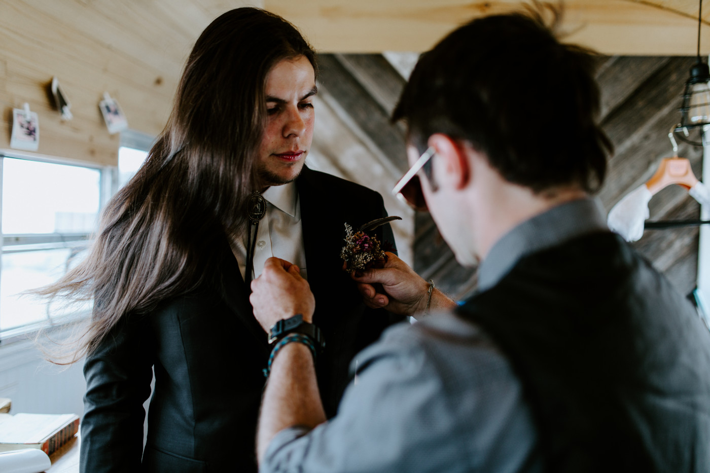 Cameron's friend helps attach the boutineer to cameron's suit.