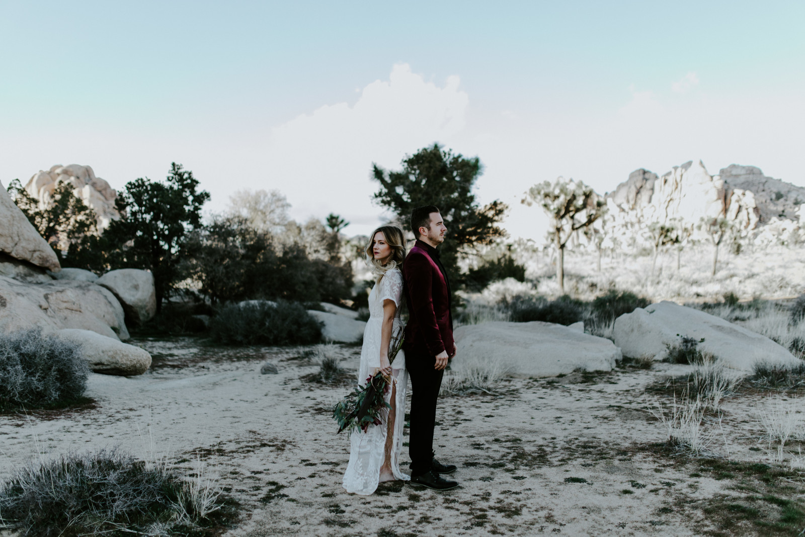 Alyssa and Jeremy stand back to back at Joshua Tree National Park. Elopement wedding photography at Joshua Tree National Park by Sienna Plus Josh.