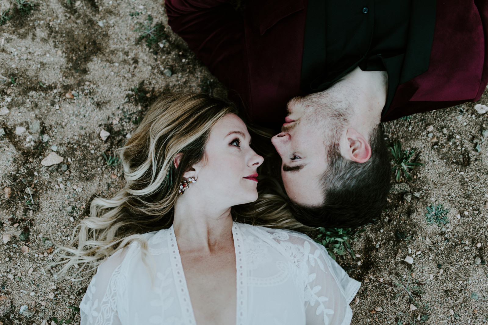 Alyssa and Jeremy kiss lay head to head on the sand at Joshua Tree. Elopement wedding photography at Joshua Tree National Park by Sienna Plus Josh.