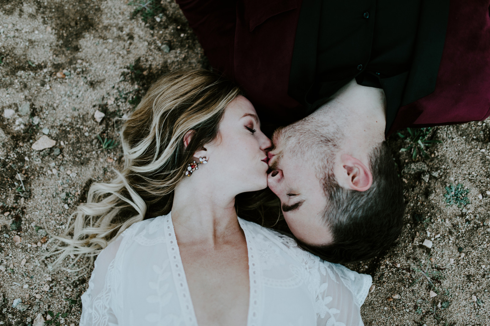Alyssa and Jeremy kiss lay head to head on the sand at Joshua Tree. Elopement wedding photography at Joshua Tree National Park by Sienna Plus Josh.