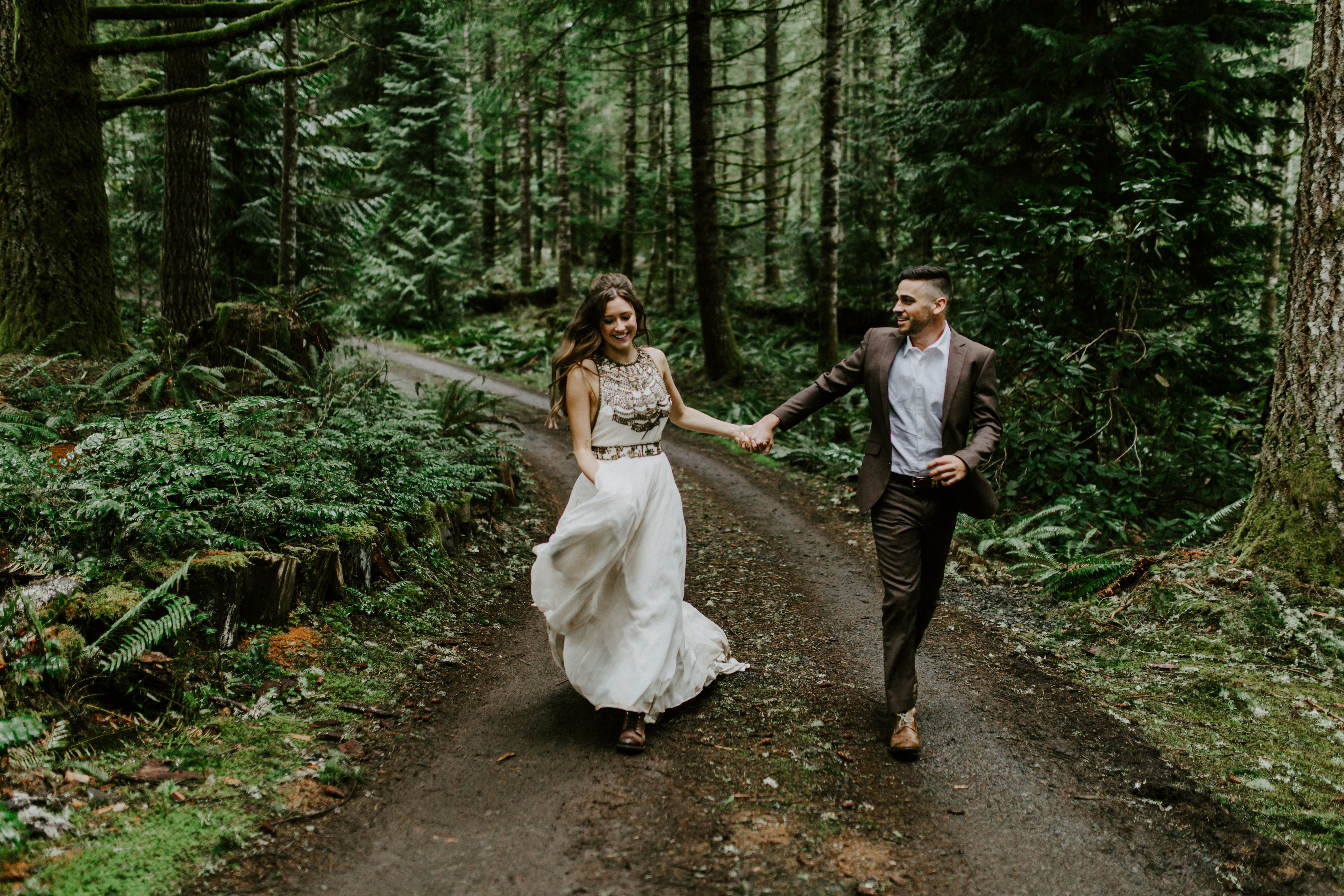 A couple runs down a path after their elopement.