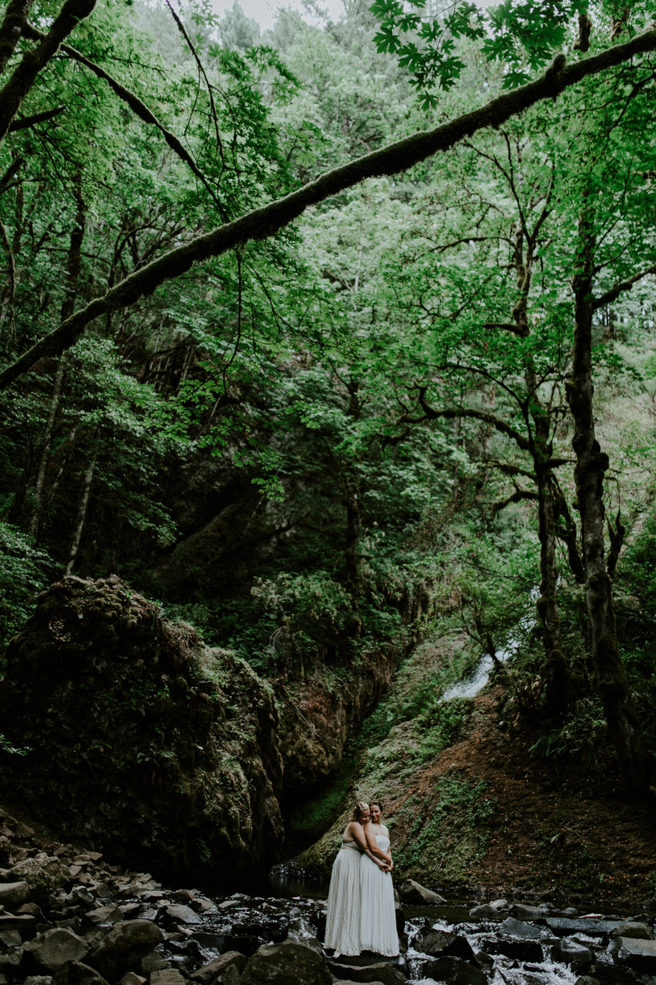 Kate and Audrey stand in the middle of a stream. Elopement wedding photography at Bridal Veil Falls by Sienna Plus Josh.