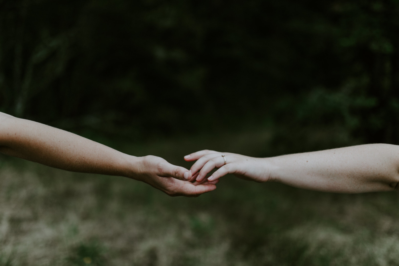 Kate and Audrey reach for each others hands. Elopement wedding photography at Bridal Veil Falls by Sienna Plus Josh.