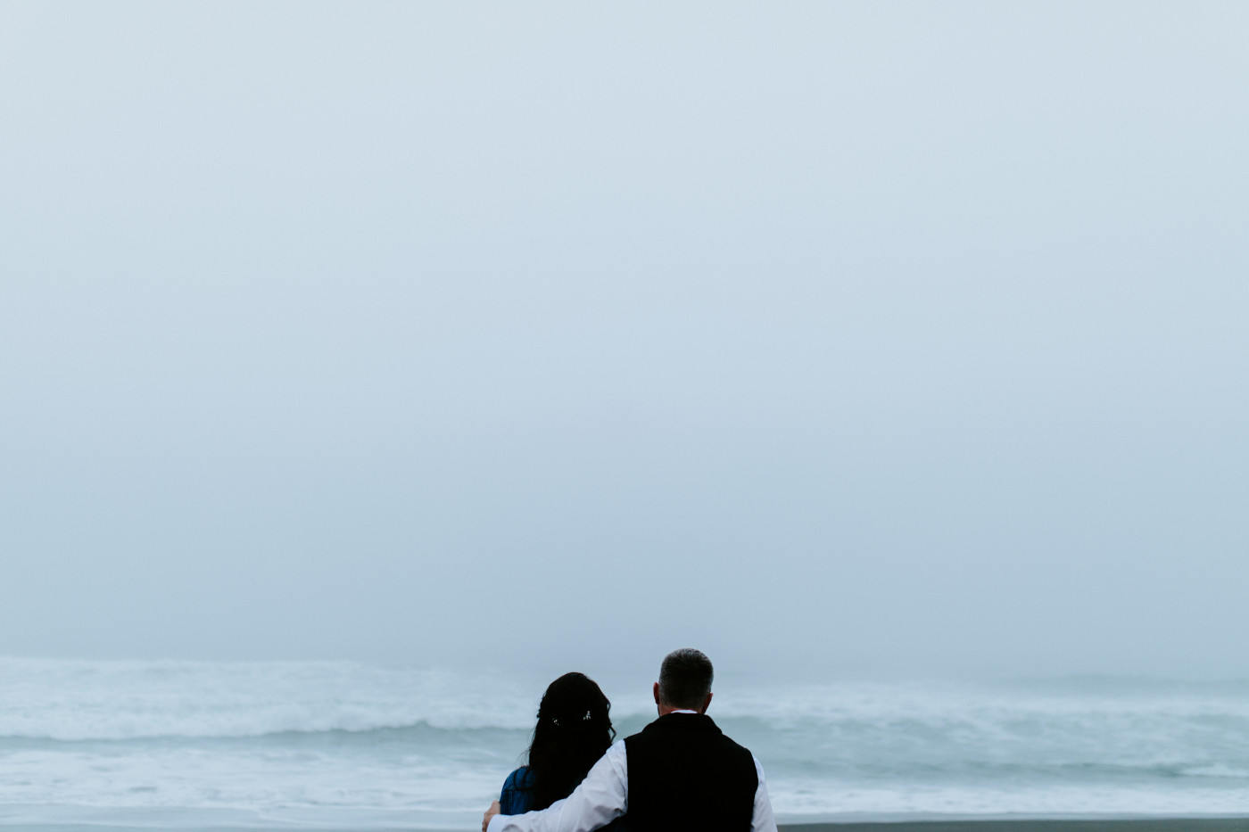 Hannah and Tim hold each other while looking at the ocean.