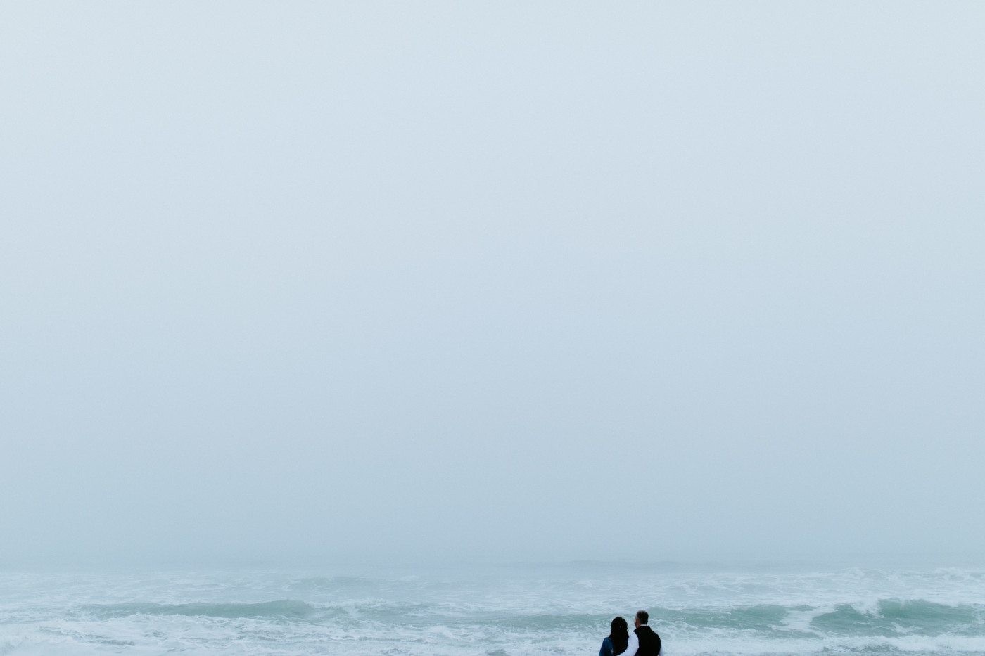 Hannah and Tim stand in front of the ocean.