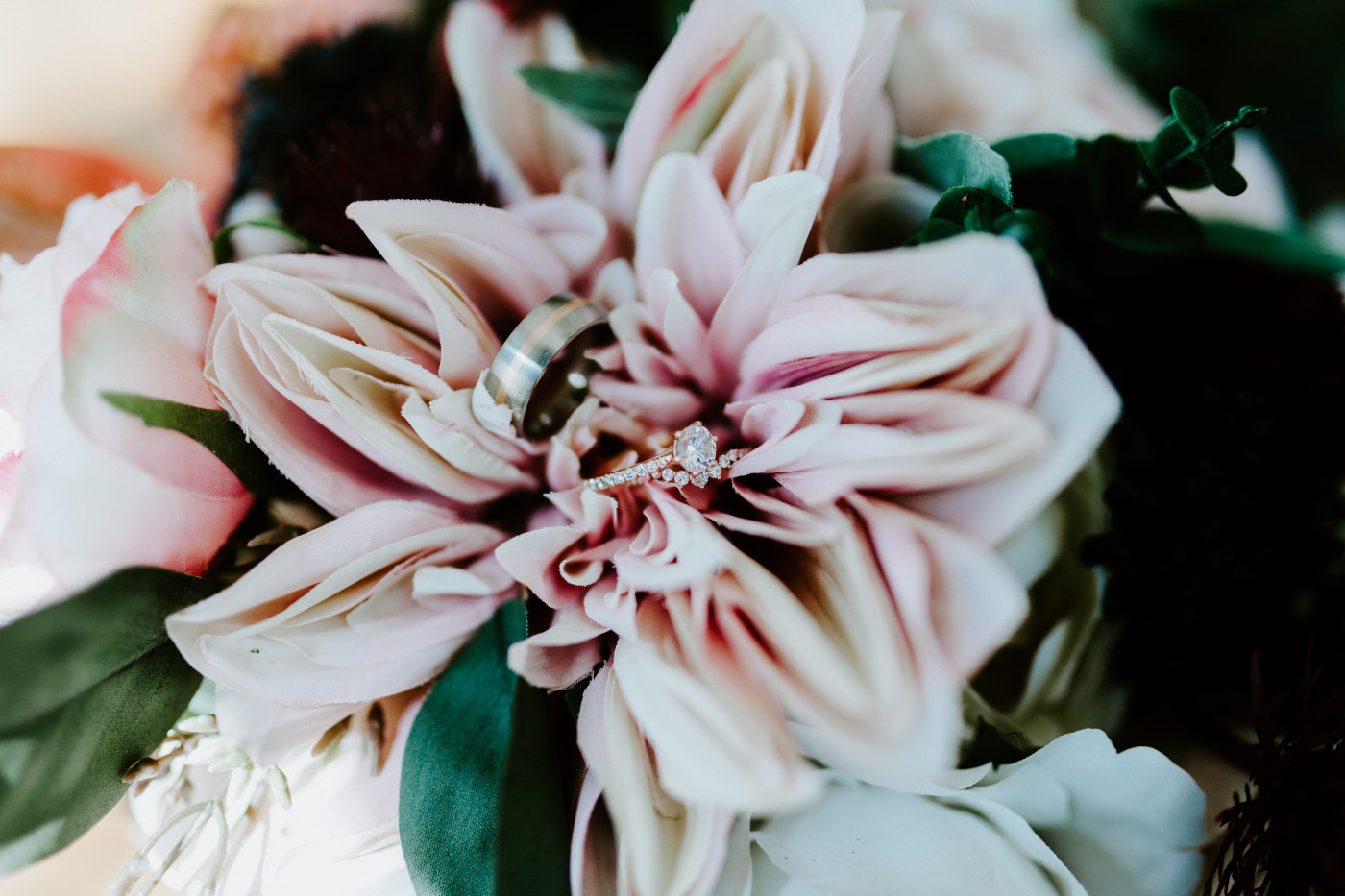 Wedding rings sit on top of a bouquet.