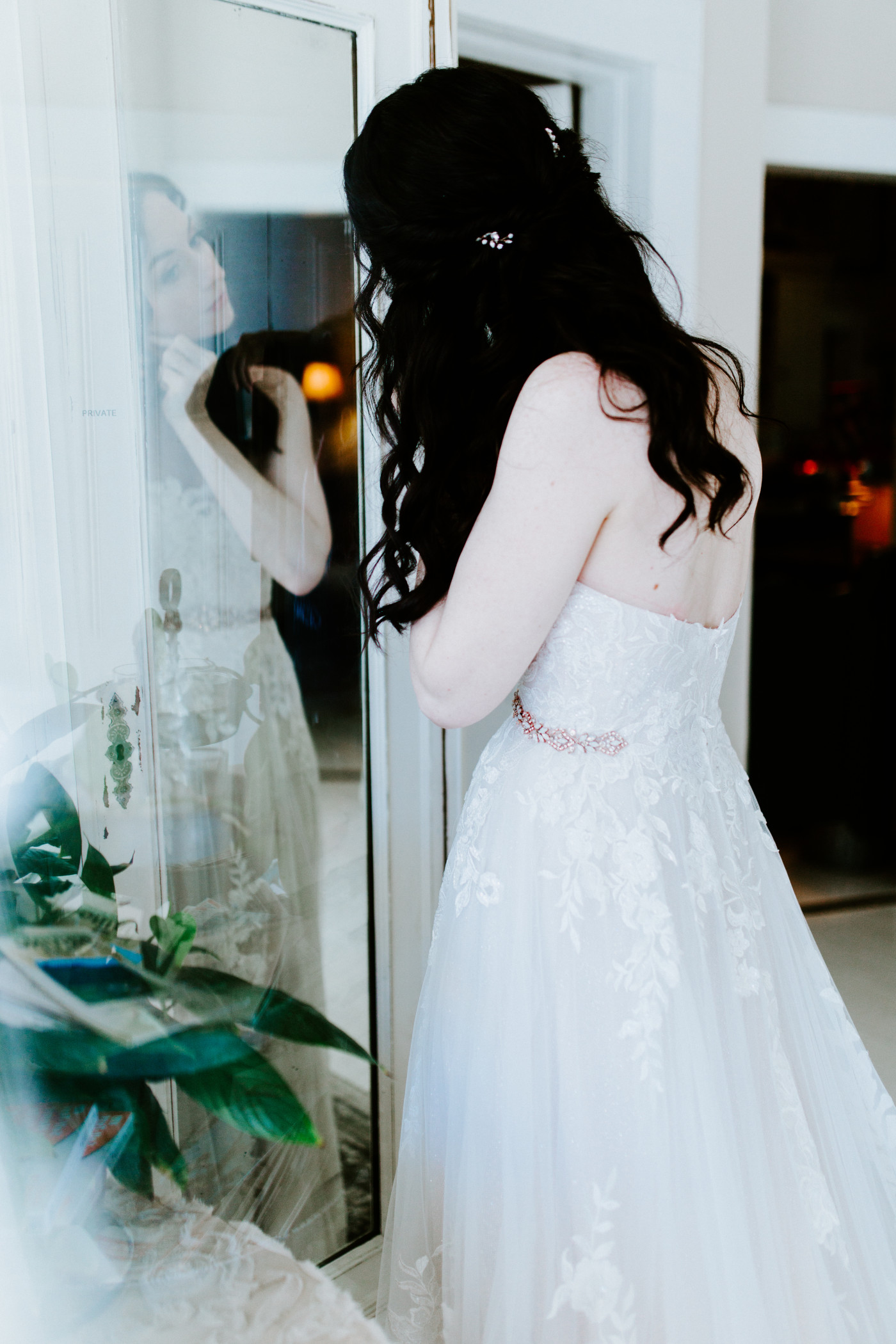 Hannah, dressed in her wedding dress, puts in earrings.