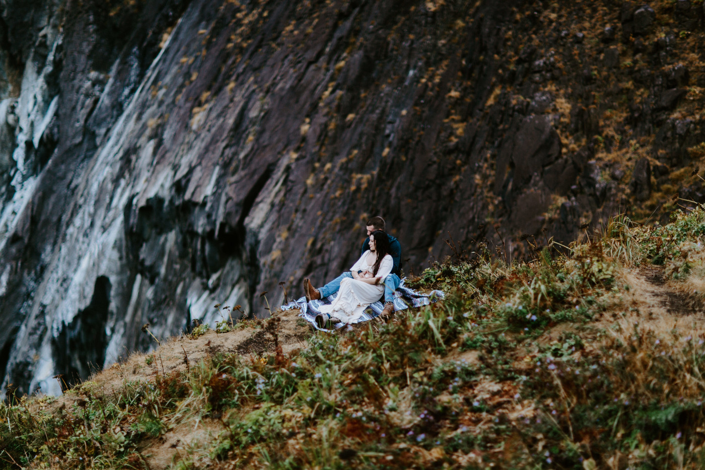 TJ and Allison sit in front of the cliff.