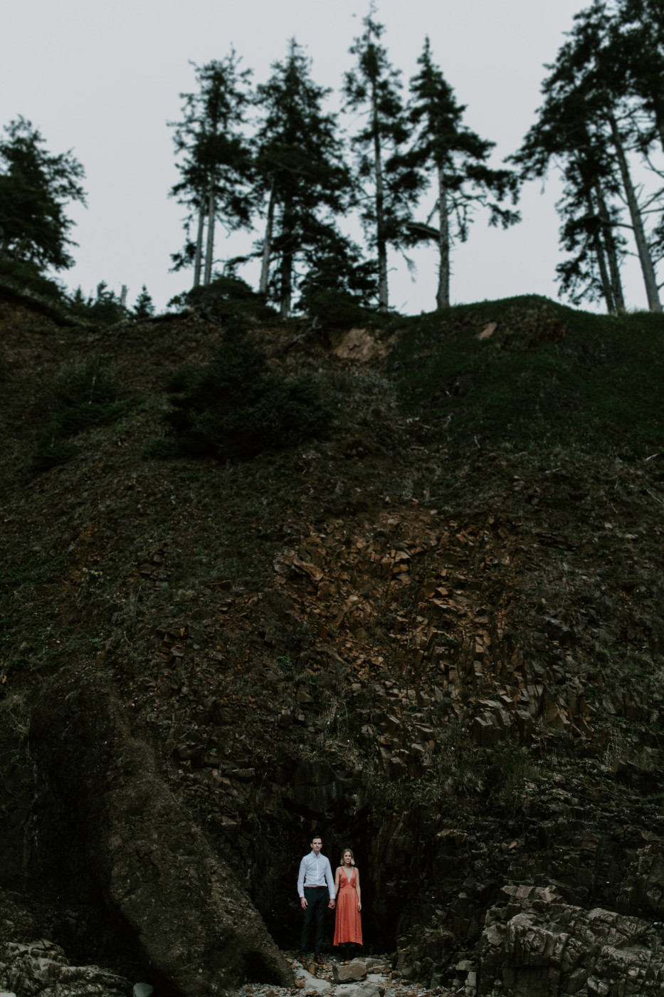 Chelsey and Billy stand side by side in front of a cliff. Elopement wedding photography at Cannon Beach by Sienna Plus Josh.