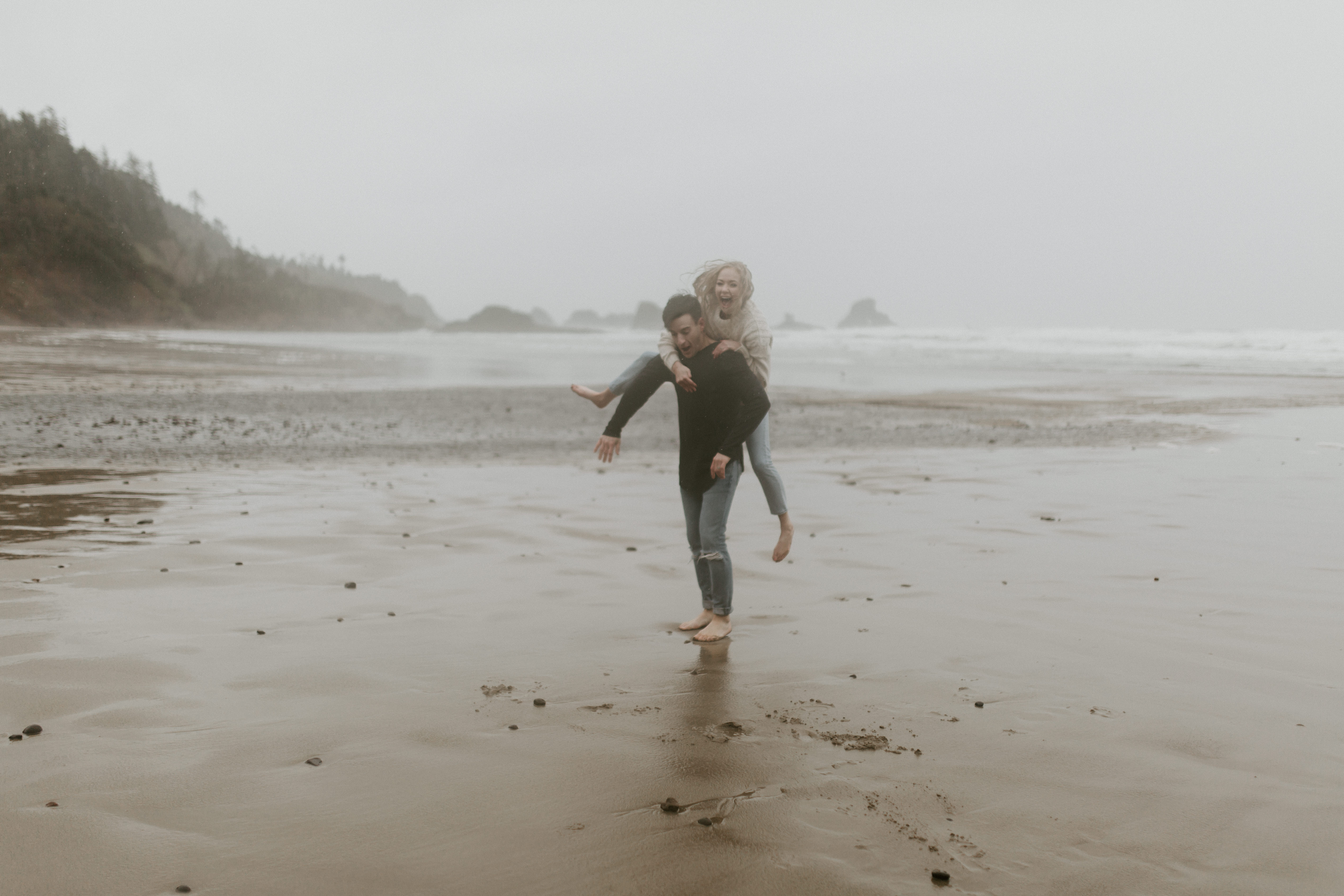 Grant gives Hannah a piggyback ride on Indian Beach in Ecola State Park, Oregon. Engagement photography in Oregon by Sienna Plus Josh.