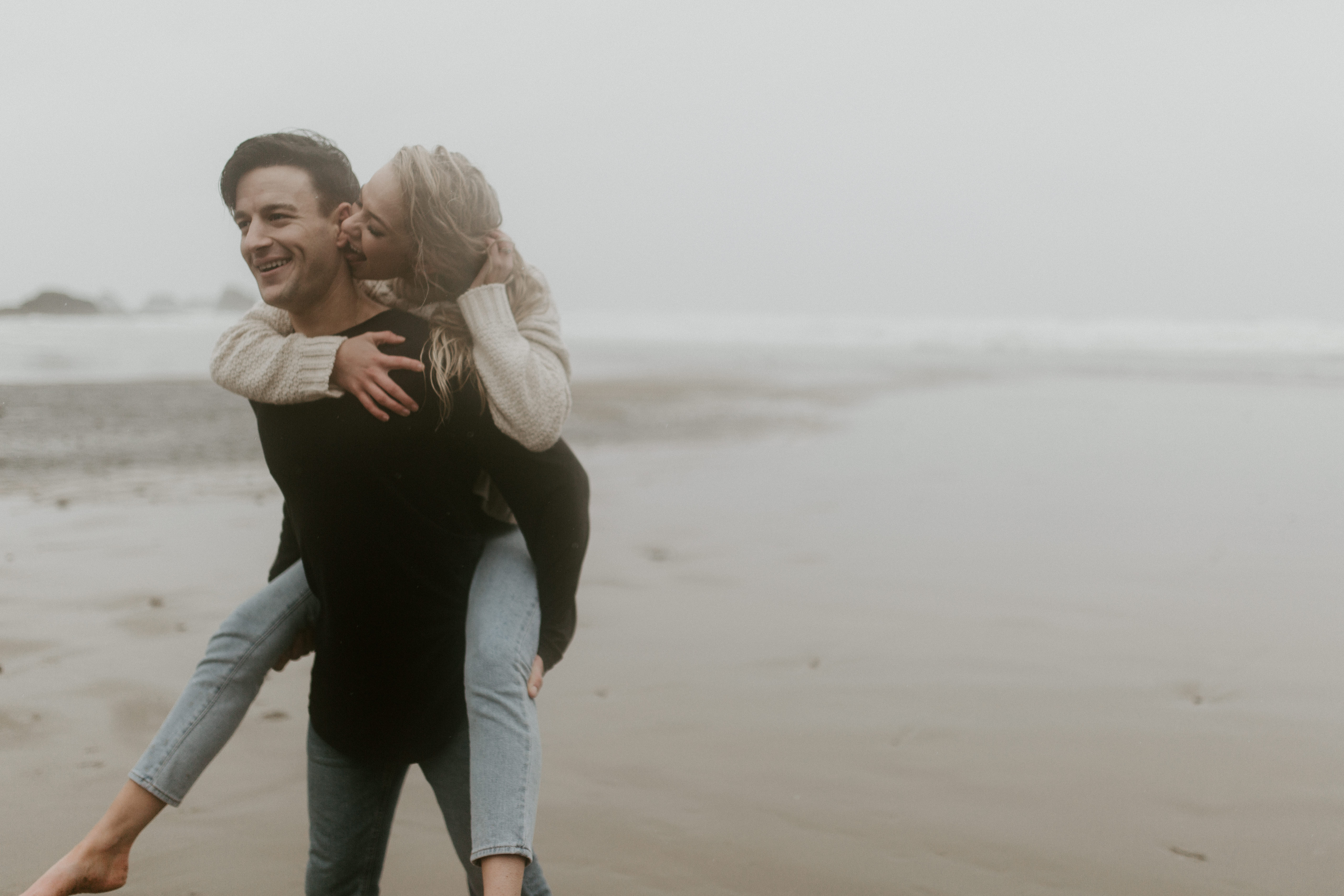 Grant gives Hannah a piggyback ride along Indian Beach in Ecola State Park, Oregon. Engagement photography in Oregon by Sienna Plus Josh.