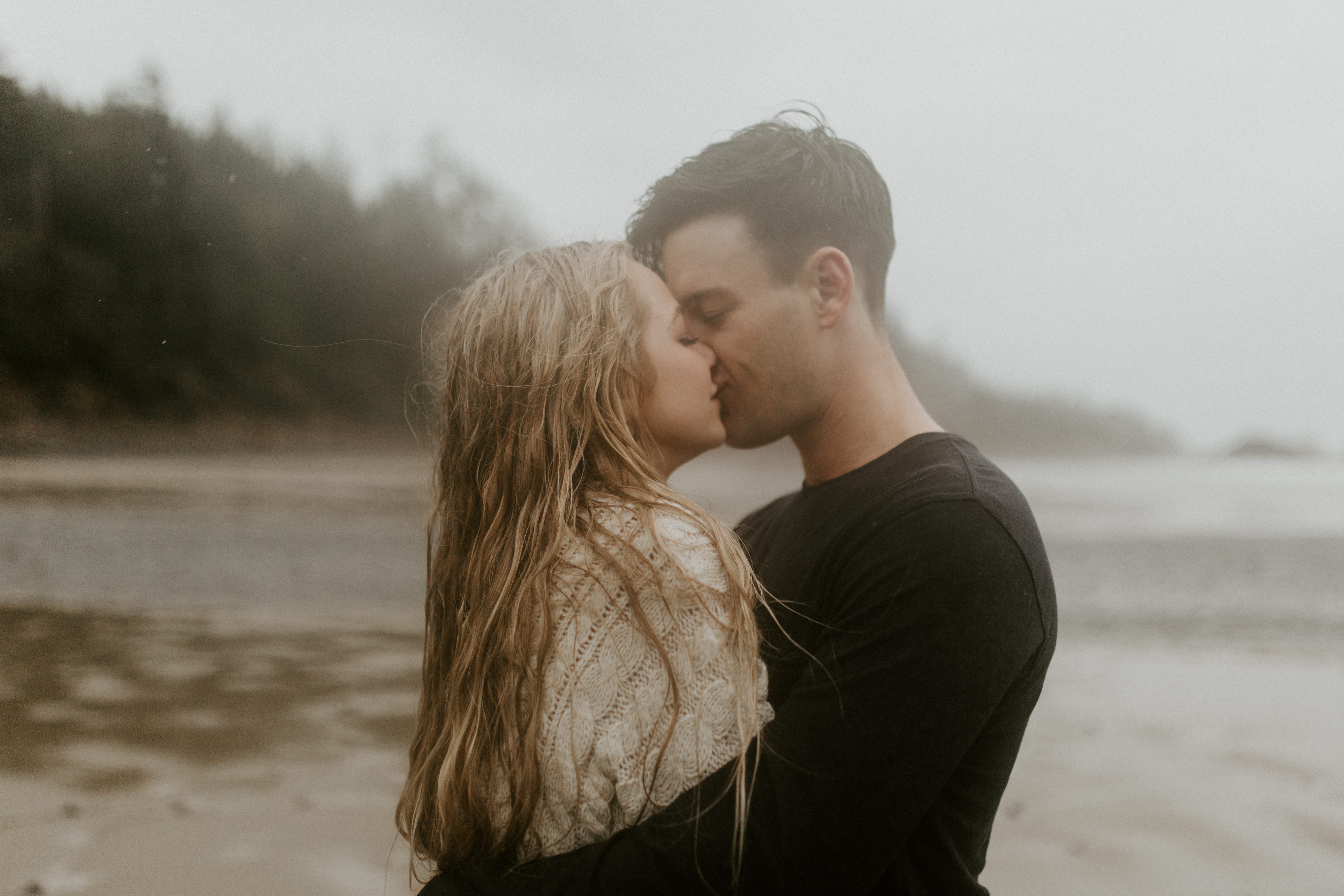 Hannah and Grant kiss in the rain on Indian Beach in Ecola State Park, Oregon. Engagement photography in Oregon by Sienna Plus Josh.