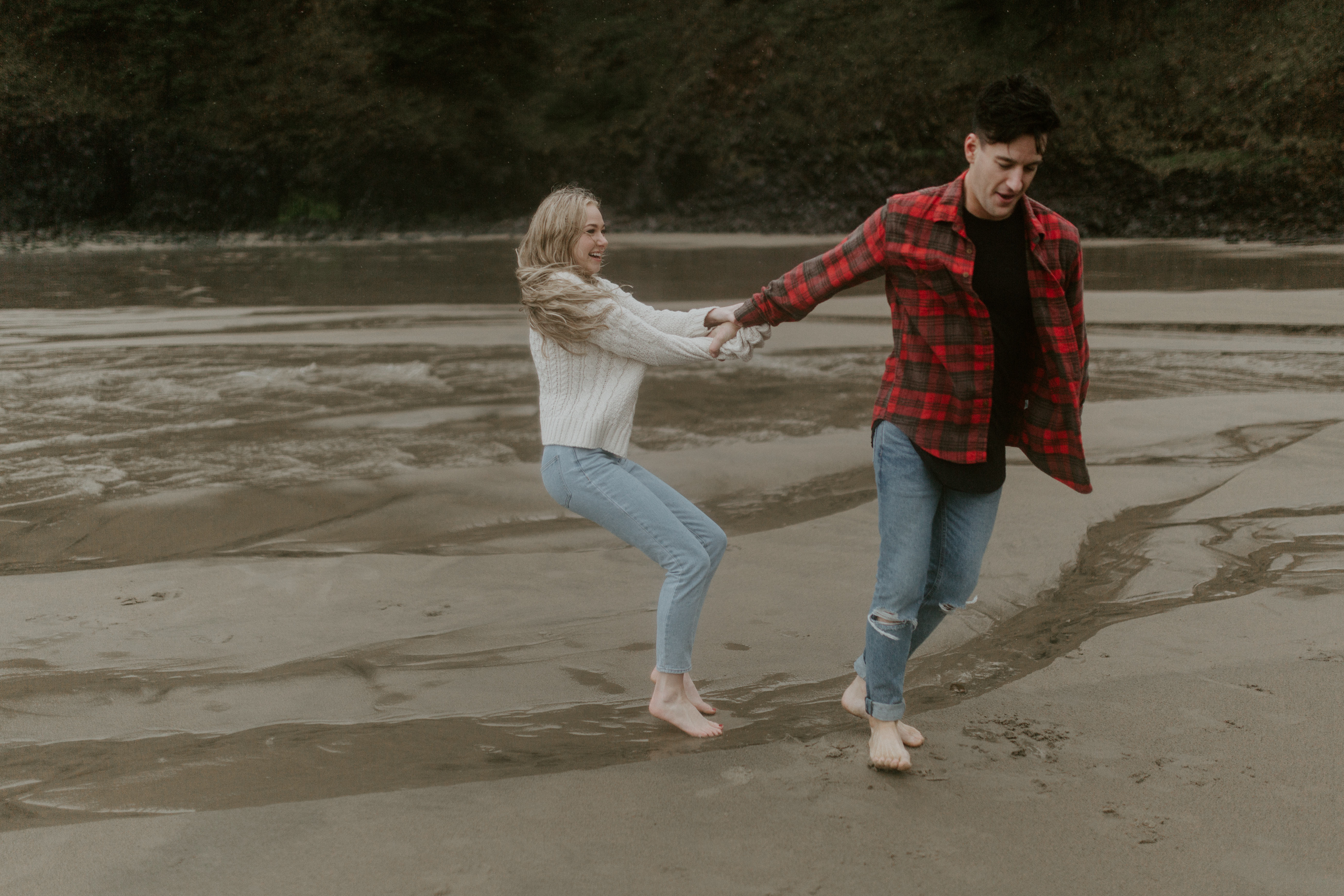 Hannah tries to lift up Grant on Indian Beach in Ecola State Park, Oregon. Engagement photography in Oregon by Sienna Plus Josh.