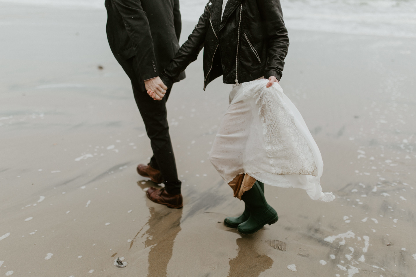 Hannah and Grant walk hand in hand on the sandy shore of Cannon Beach, Oregon. Wedding photography in Portland Oregon by Sienna Plus Josh.