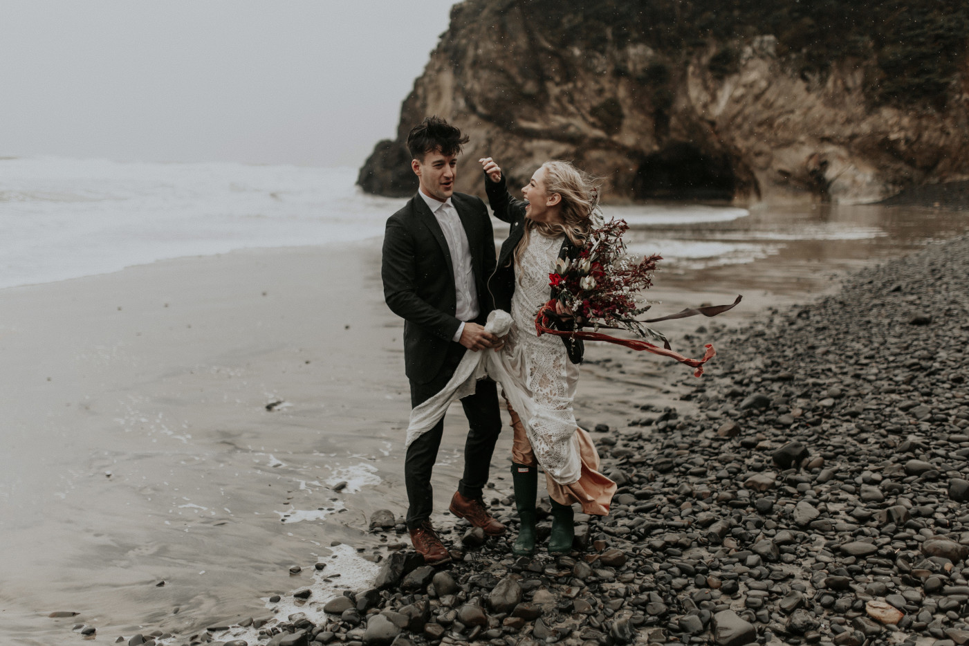 Hannah fixes Grant's fly away hair while they stand on the rocks of Cannon Beach for their Elopement in Oregon. Wedding photography in Portland Oregon by Sienna Plus Josh.