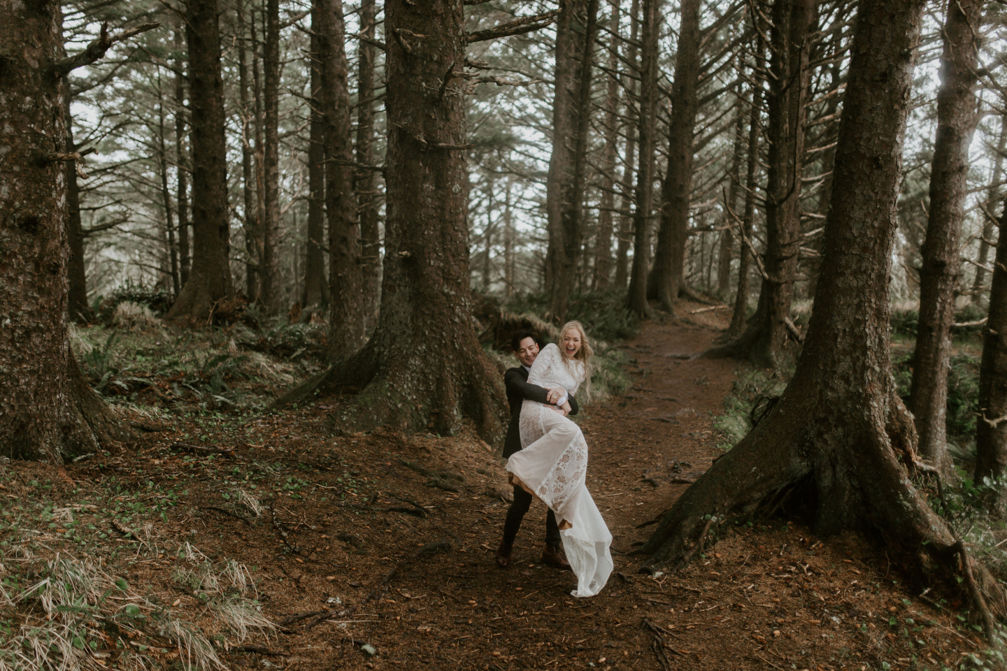 Grant lifts and spins Hannah along a path in Cannon Beach, Oregon. Wedding photography in Portland Oregon by Sienna Plus Josh.