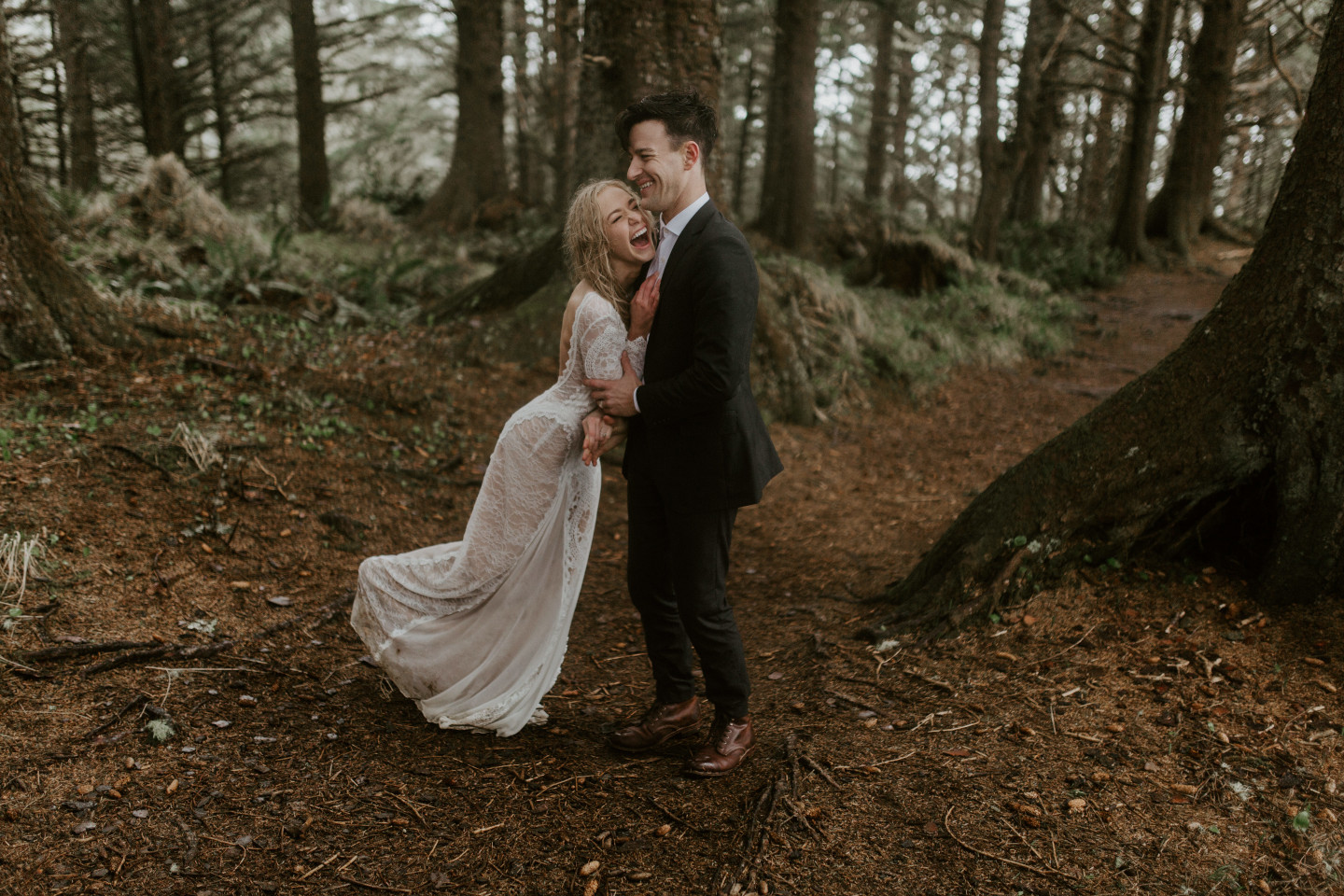 Hannah and Grant laugh while they stand on a path in Cannon Beach, Oregon. Wedding photography in Portland Oregon by Sienna Plus Josh.