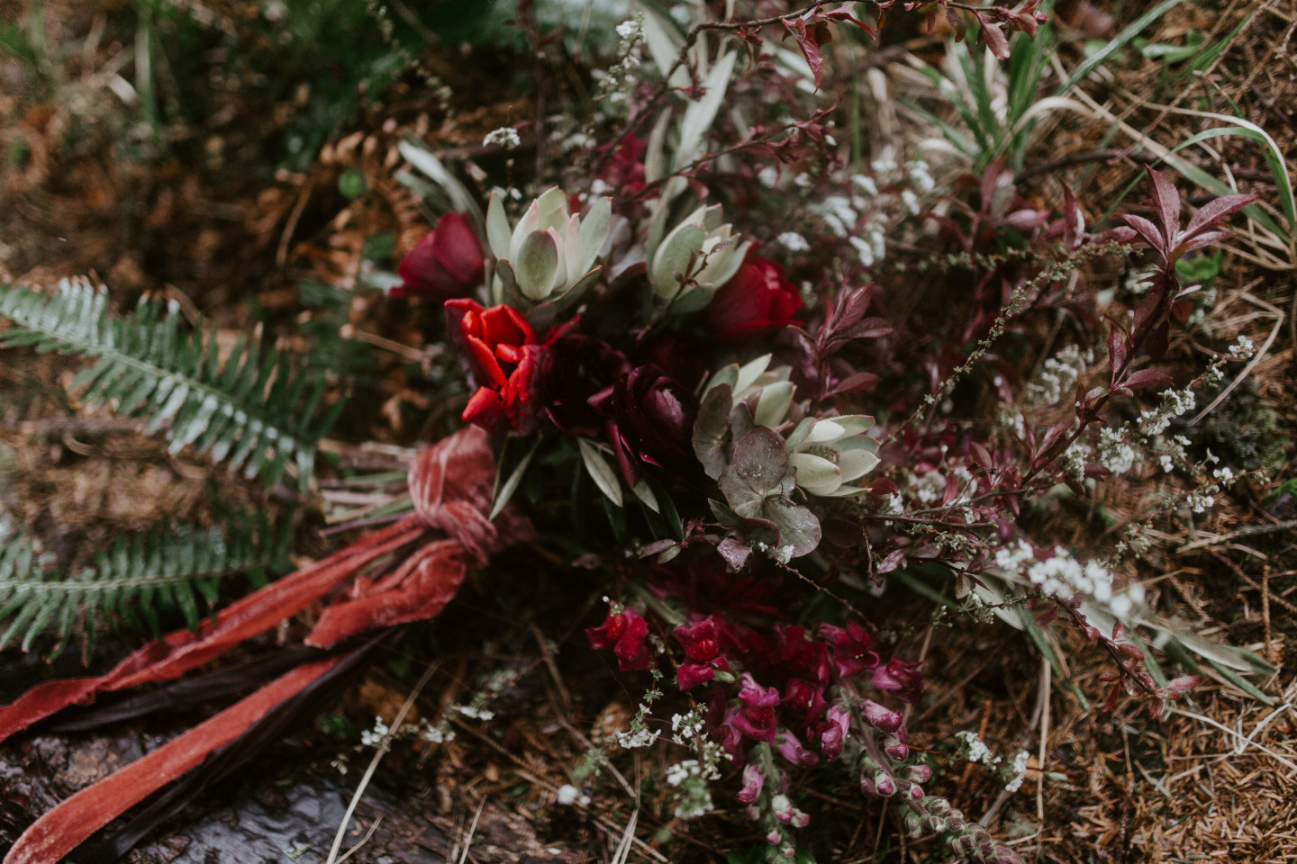 Hannah's bouquet lays on the ground of Cannon Beach, Oregon. Wedding photography in Portland Oregon by Sienna Plus Josh.