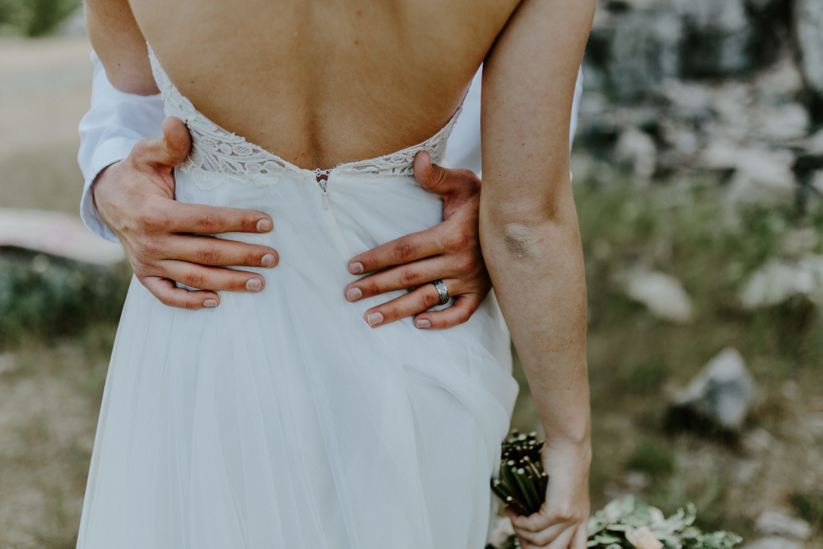 A close up of Harper's back while Trevor puts his arms around her at Cascade Locks, Oregon. Elopement photography in Portland Oregon by Sienna Plus Josh.