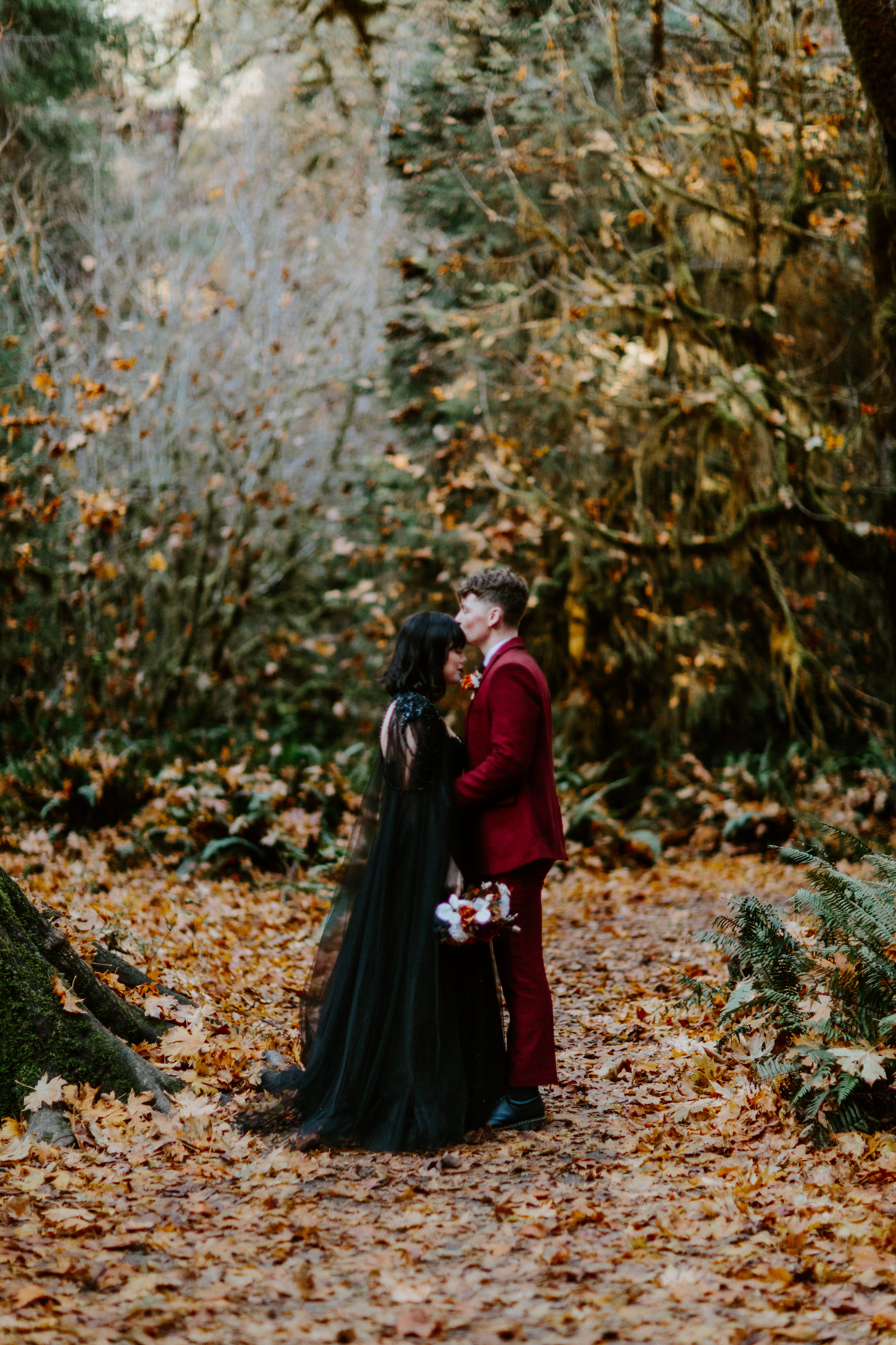 Brett kisses Bethany's forehead in the forest of the Hoh Rainforest after their elopement.
