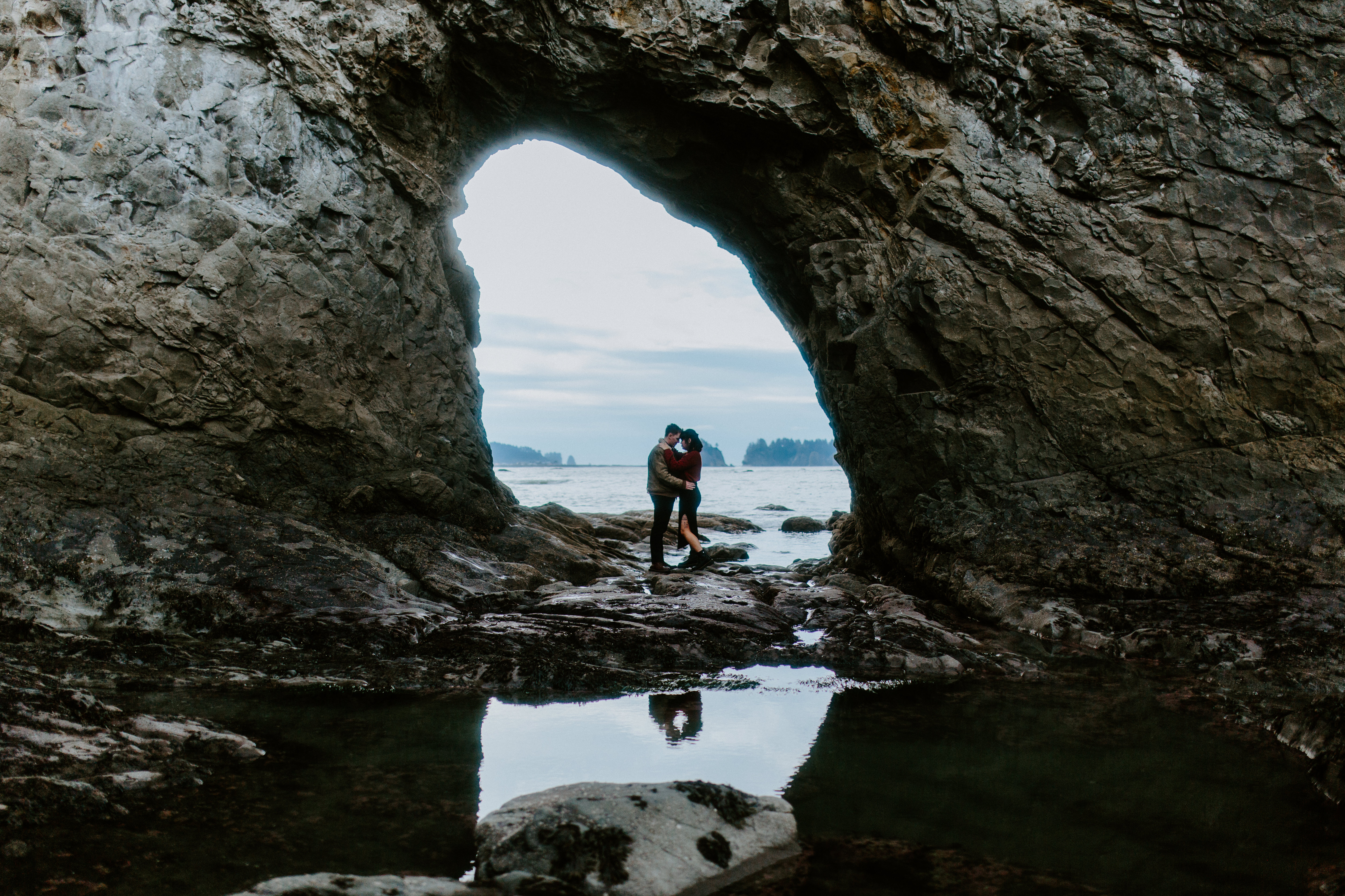 Brett and Bethany stand under a rock arch at Rialto Beach.