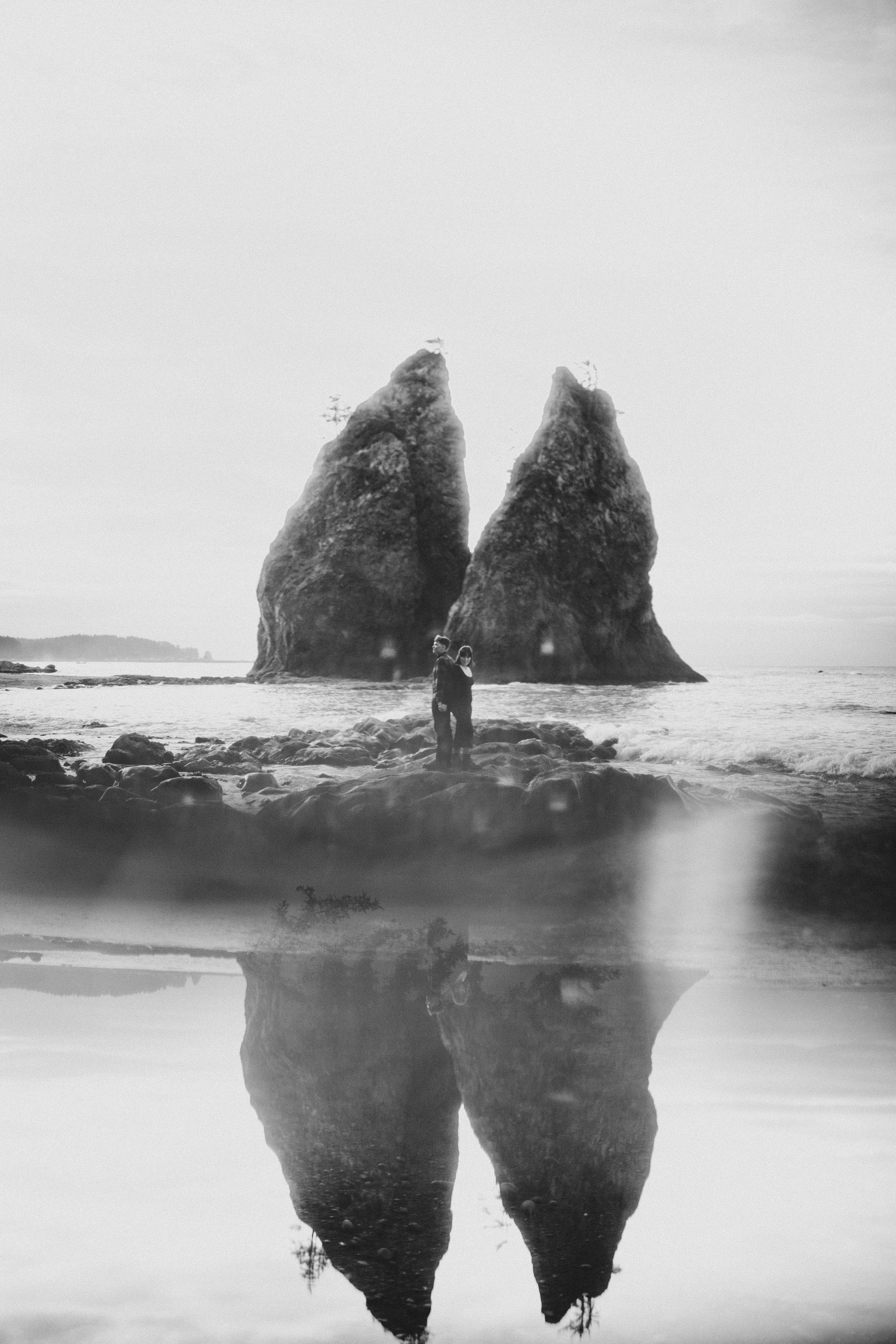 Bethany and Brett stand back to back on a rock in Rialto Beach.