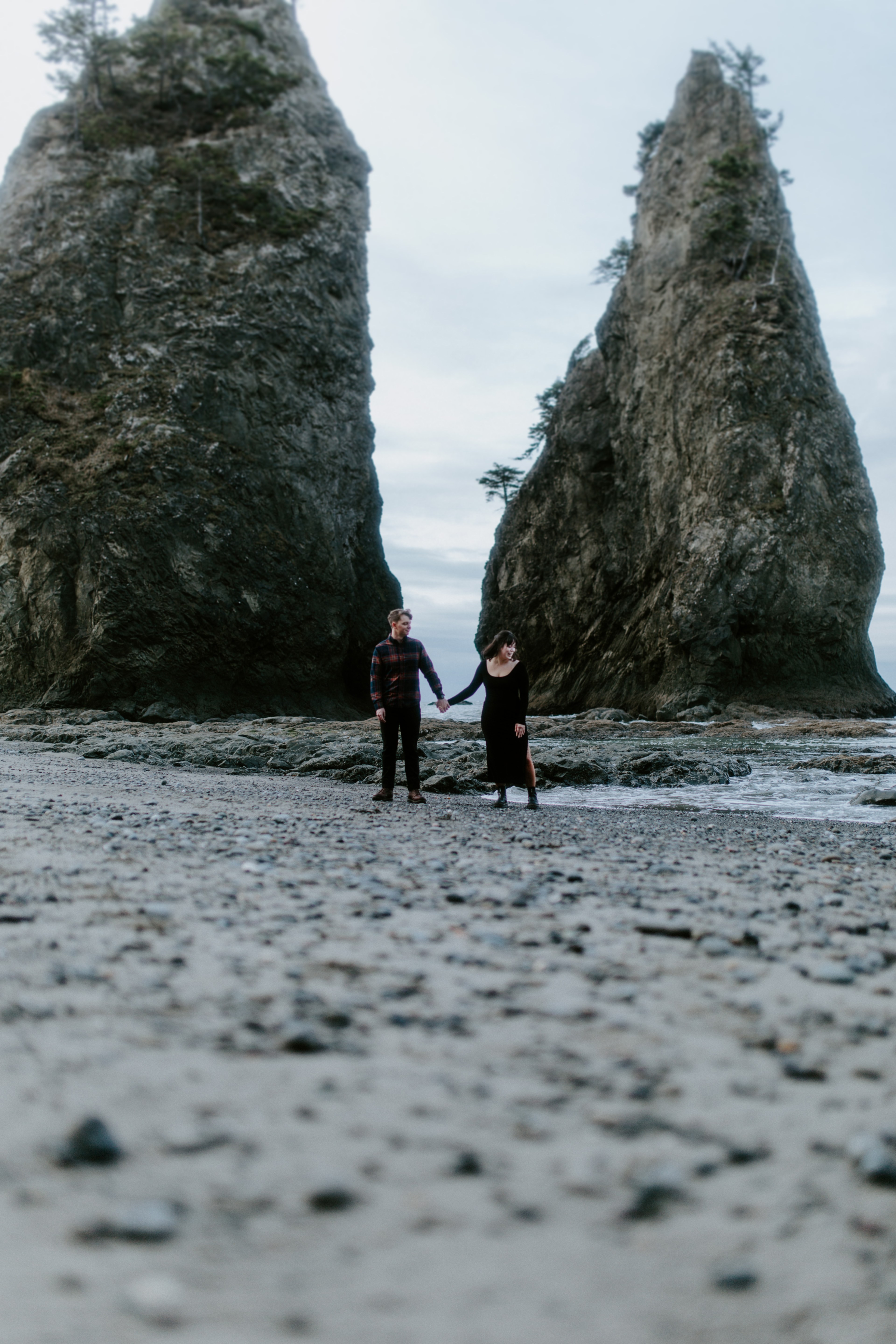 Bethany and Brett hold hands while standing on the sand at Rialto Beach.