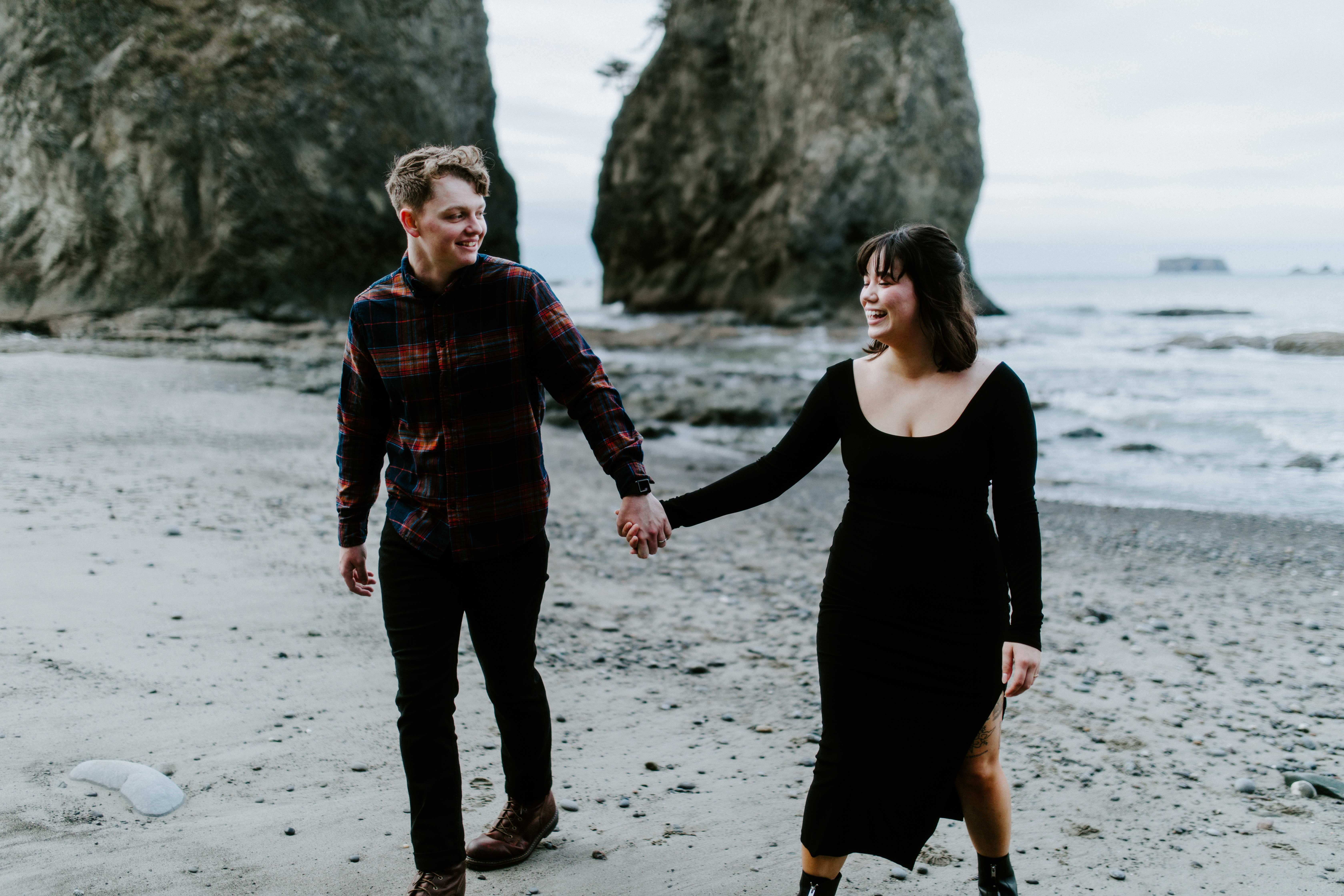 Brett and Bethany smile while holding hands at Rialto Beach, Washington.
