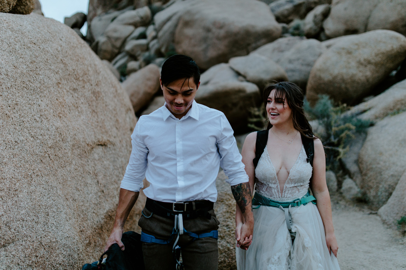 Zack and Shelby walk hand in hand in their rock climbing gear.