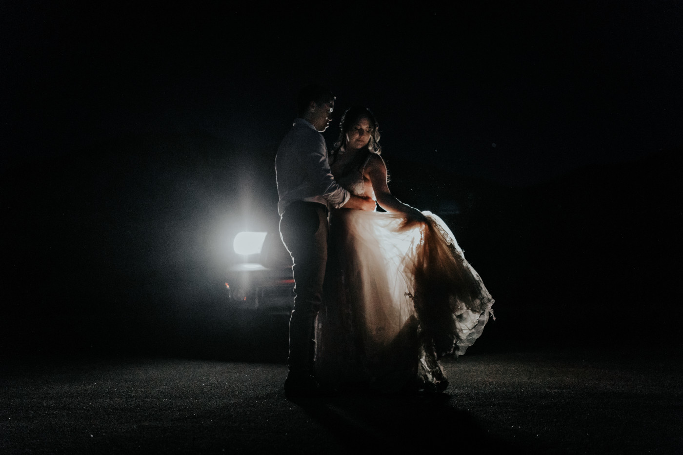 Shelby holds her dress while Zack holds her.