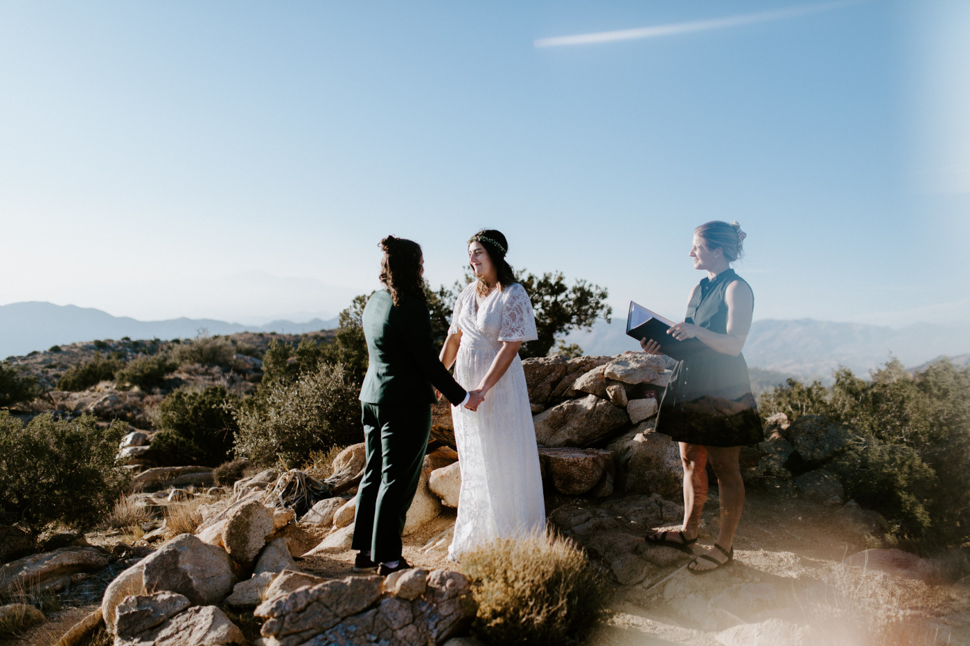 Madison and Becca stand hand in hand in the Joshua Tree desert.