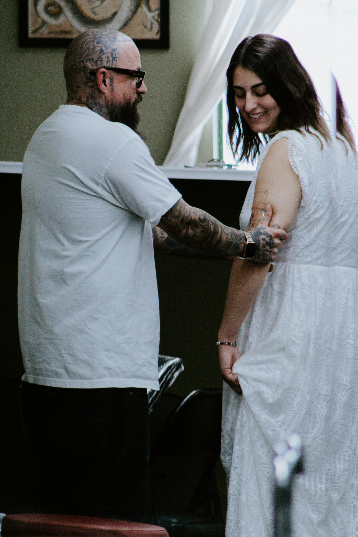 The tattooist inspects his work.