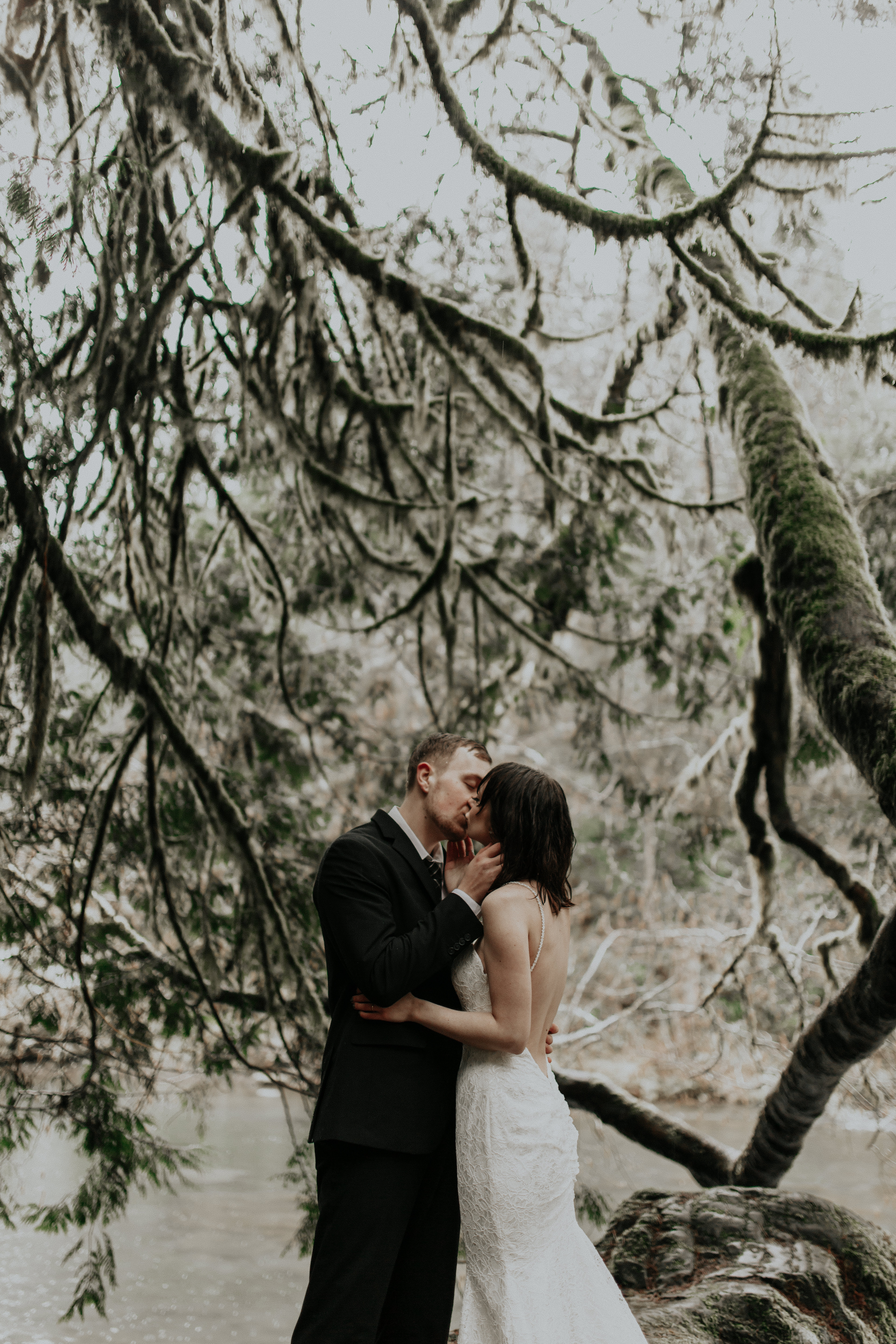 TJ and Paige find shelter under a tree alongside Moulton Falls river in Washington for their adventure wedding.