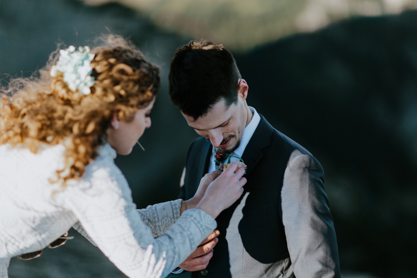 Tasha pins a boutineer to Chad. Elopement photography at Mount Rainier by Sienna Plus Josh.