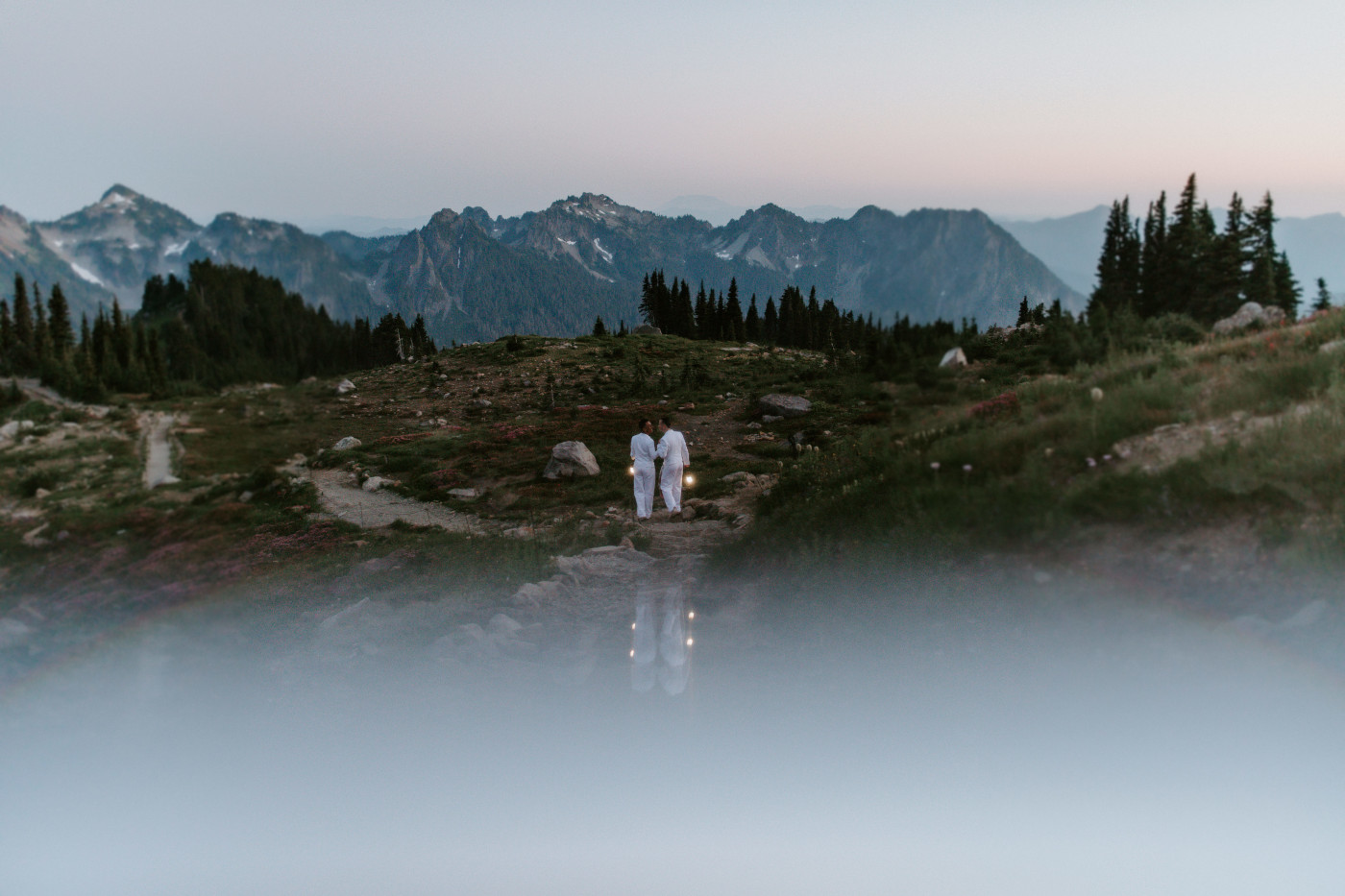 Brooks and Fred kiss on a trail while holding lanterns in Mount Rainier.