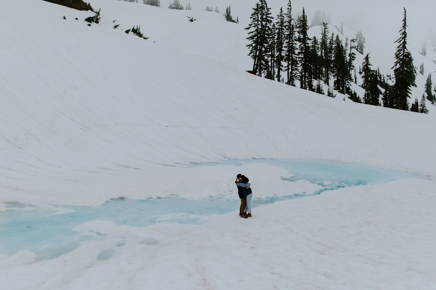 Taylor and Kyle hug by the blue water. Elopement photography at North Cascades National Park by Sienna Plus Josh.