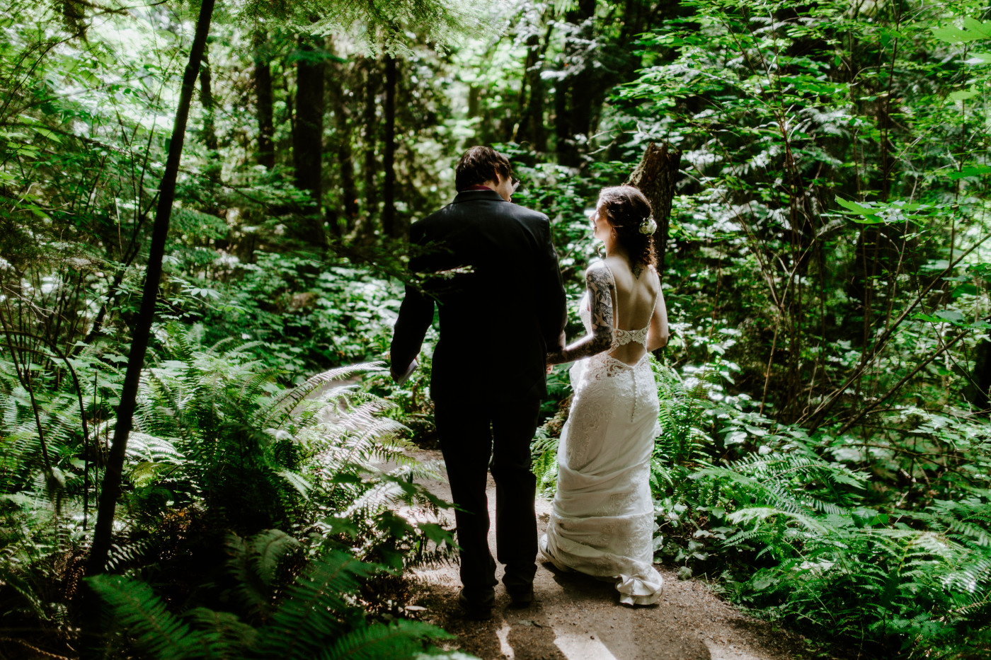 The bride and groom walk through the forest of Olympic National Park.