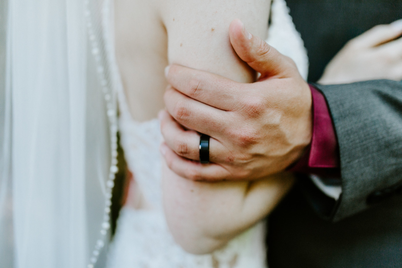 A close up of the ring on the grooms finger.