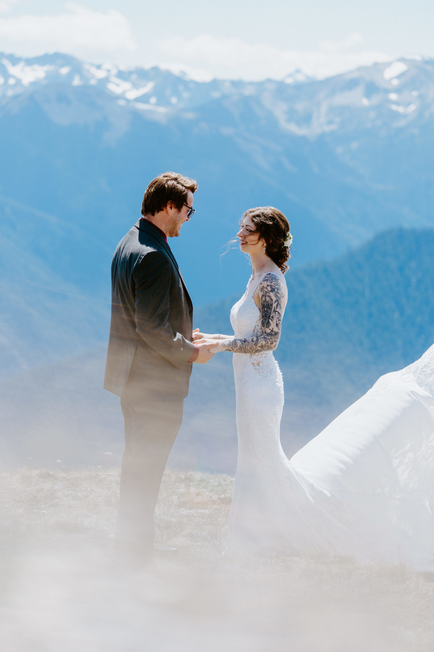 The groom and bride stand in front of a mountain at Olympic National Park.