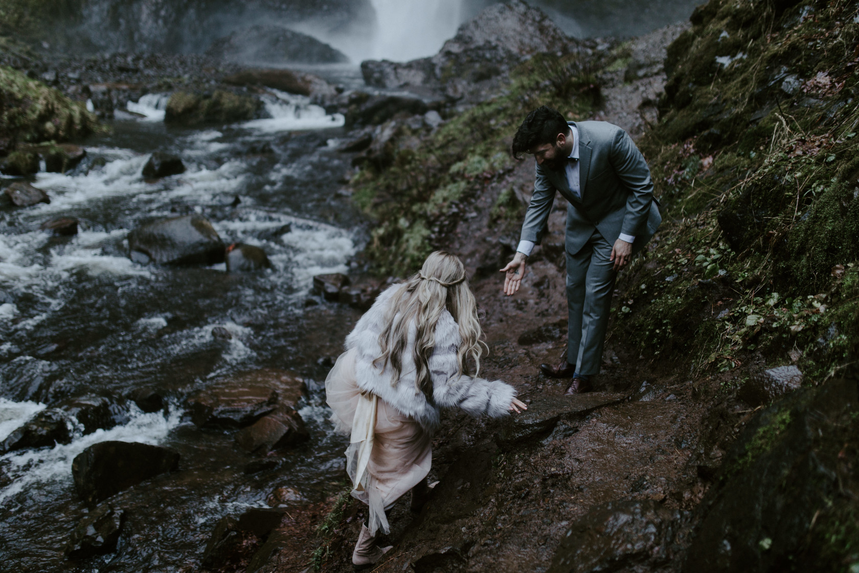 Boris holds out a hand for Tyanna as they venture toward the base of Latourell Falls. Adventure elopement in the Columbia River Gorge by Sienna Plus Josh.